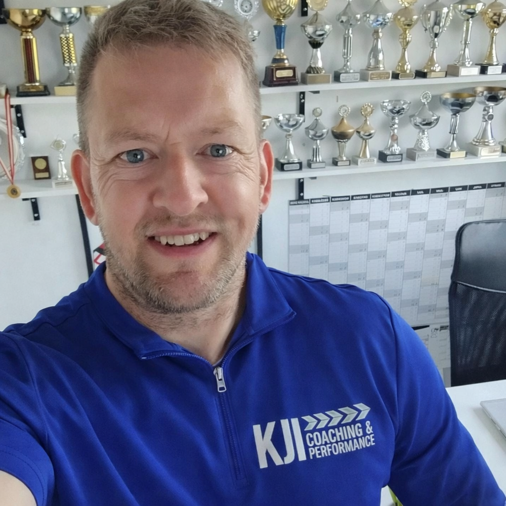 Knud Juhl Iversen – KJI Coaching & Performance, med pokaler i baggrunden